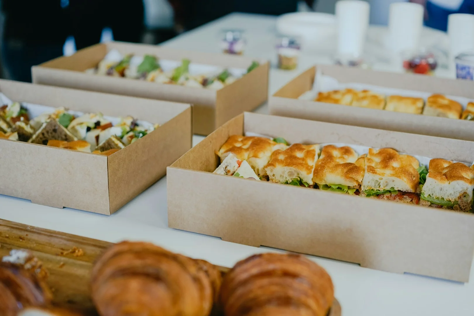 Catering boxes filled with sandwiches prepared for school hot lunch programs.