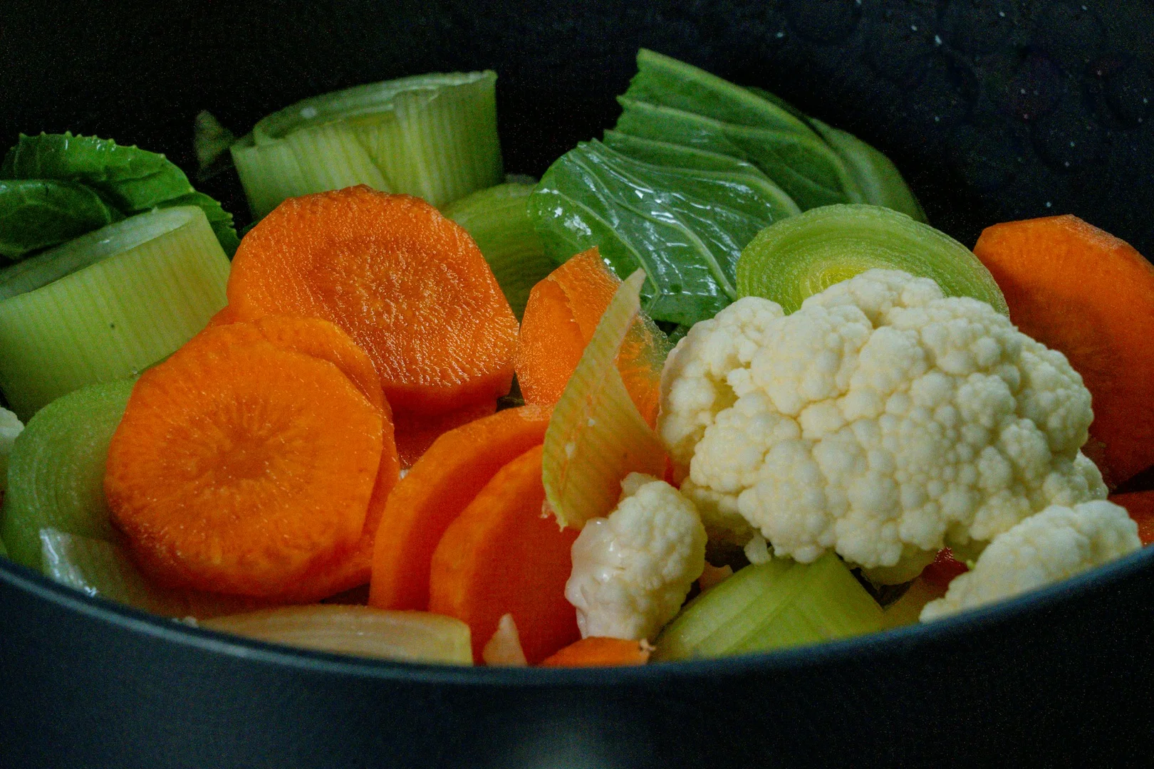 Fresh vegetables including cauliflower, carrots, and greens in a bowl for healthy vegetarian school lunch.