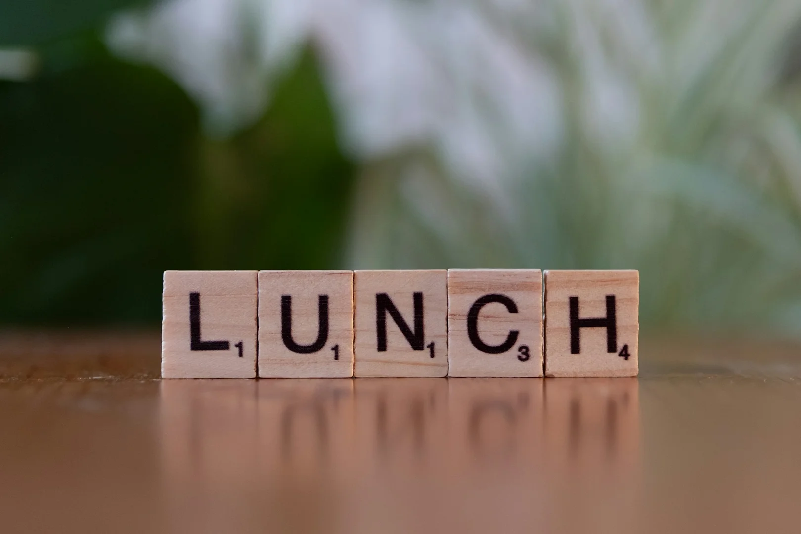 Wooden letter tiles spelling the word lunch on a table, representing school lunch programs.