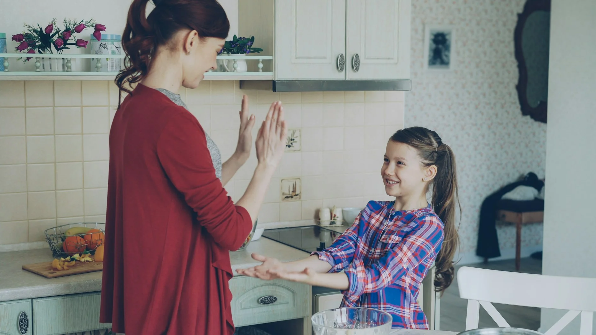 A parent and child smiling and working together in the kitchen during lunch preparation.