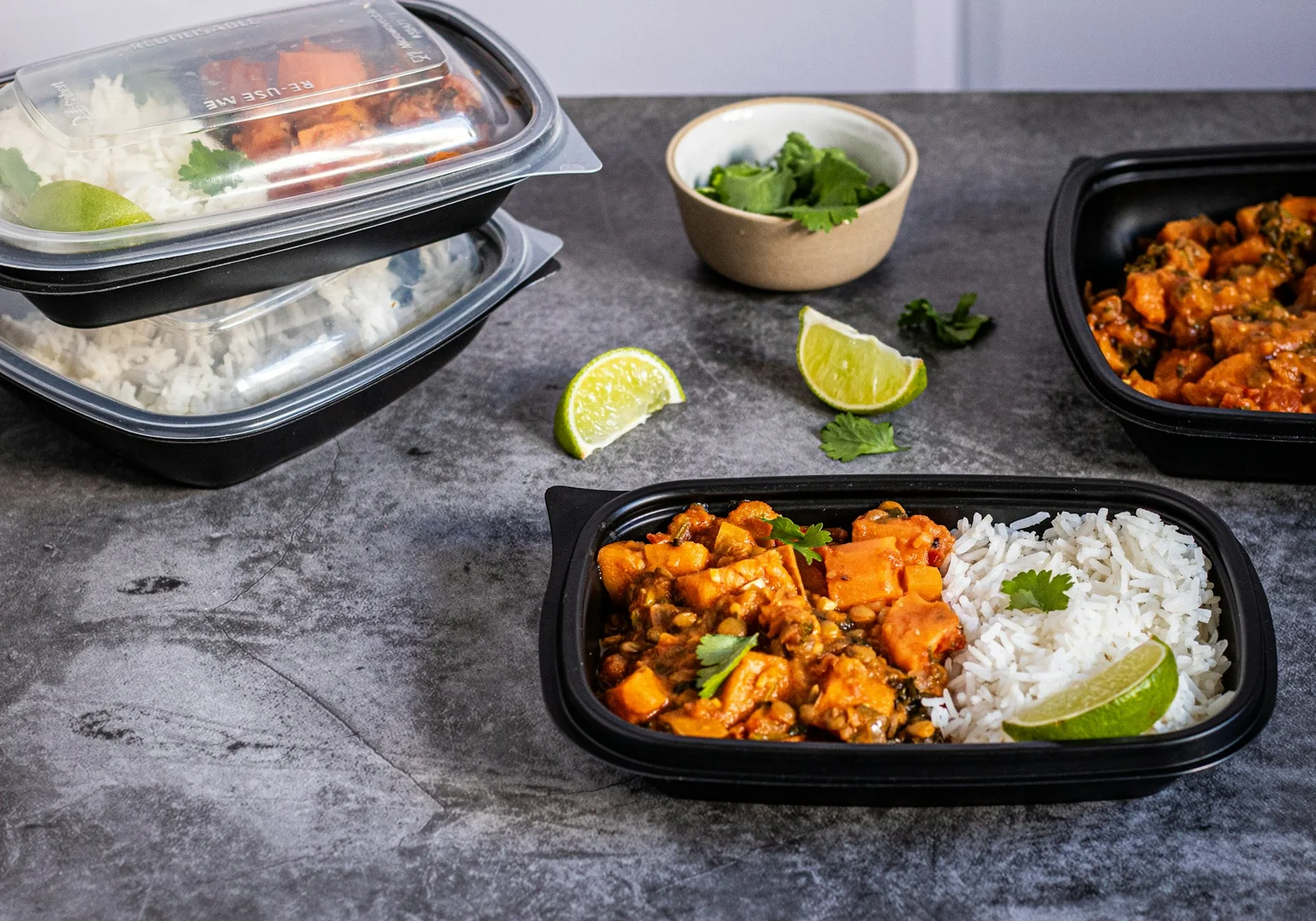 Prepared hot lunch containers with rice and vegetables, showing organized meal prep for school programs.