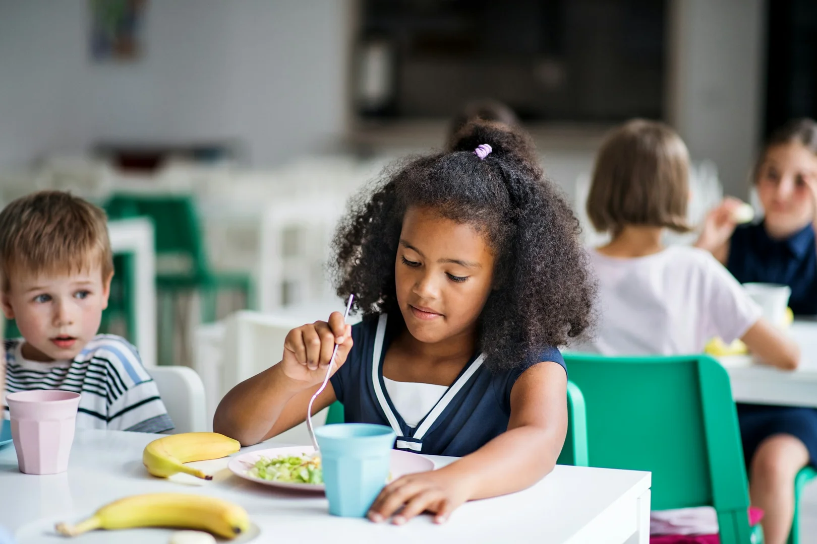 Children enjoying balanced school lunches in a cafeteria setting.