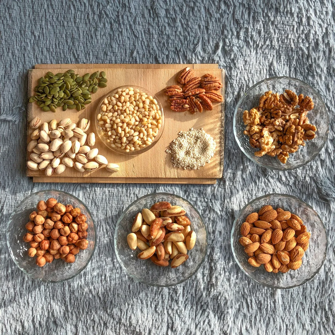 Assorted nuts displayed on a wooden board, representing allergy awareness for nut-free school lunch policies.
