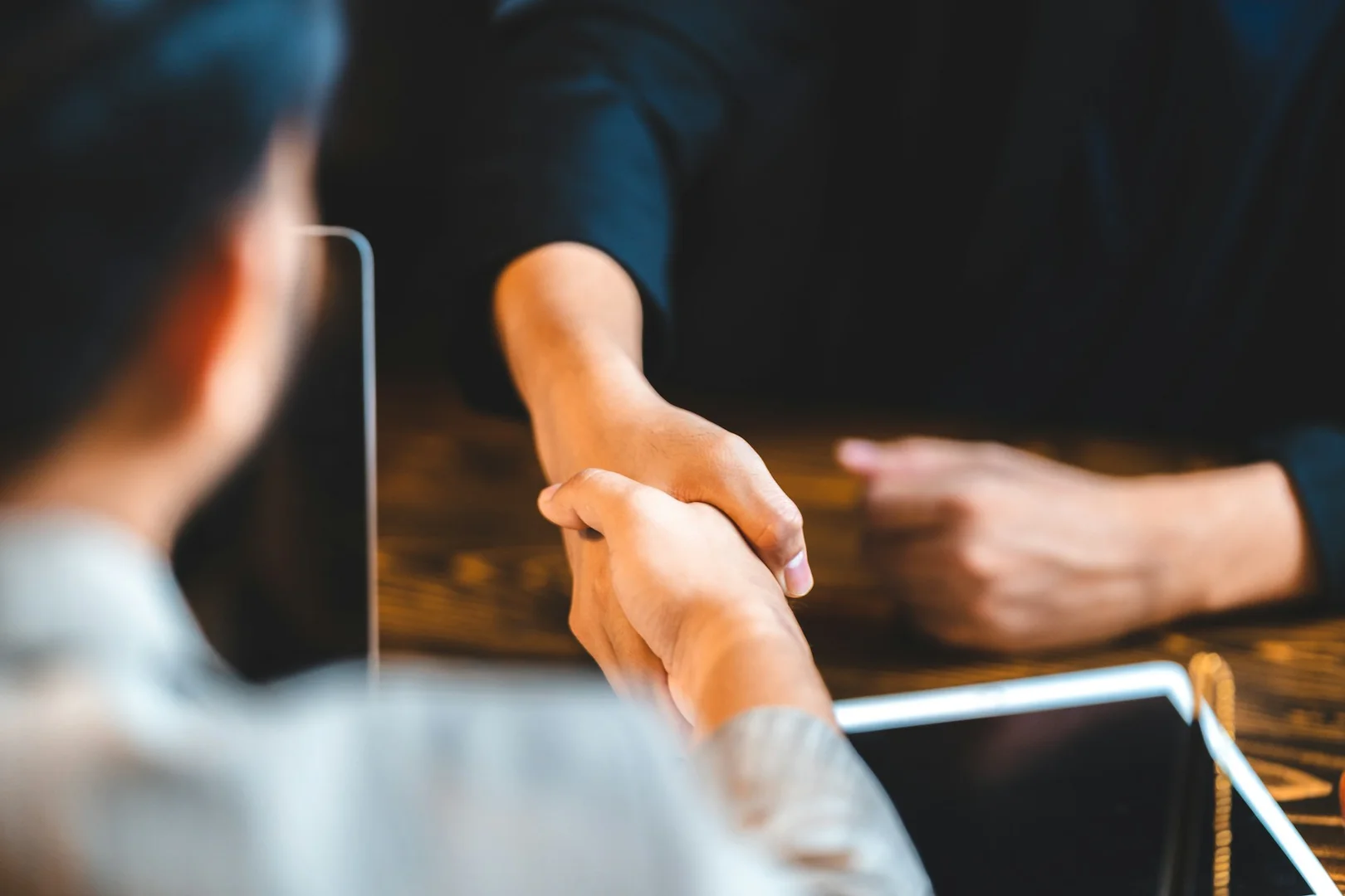 School representative and program provider shaking hands over a tablet during a hot lunch program partnership.