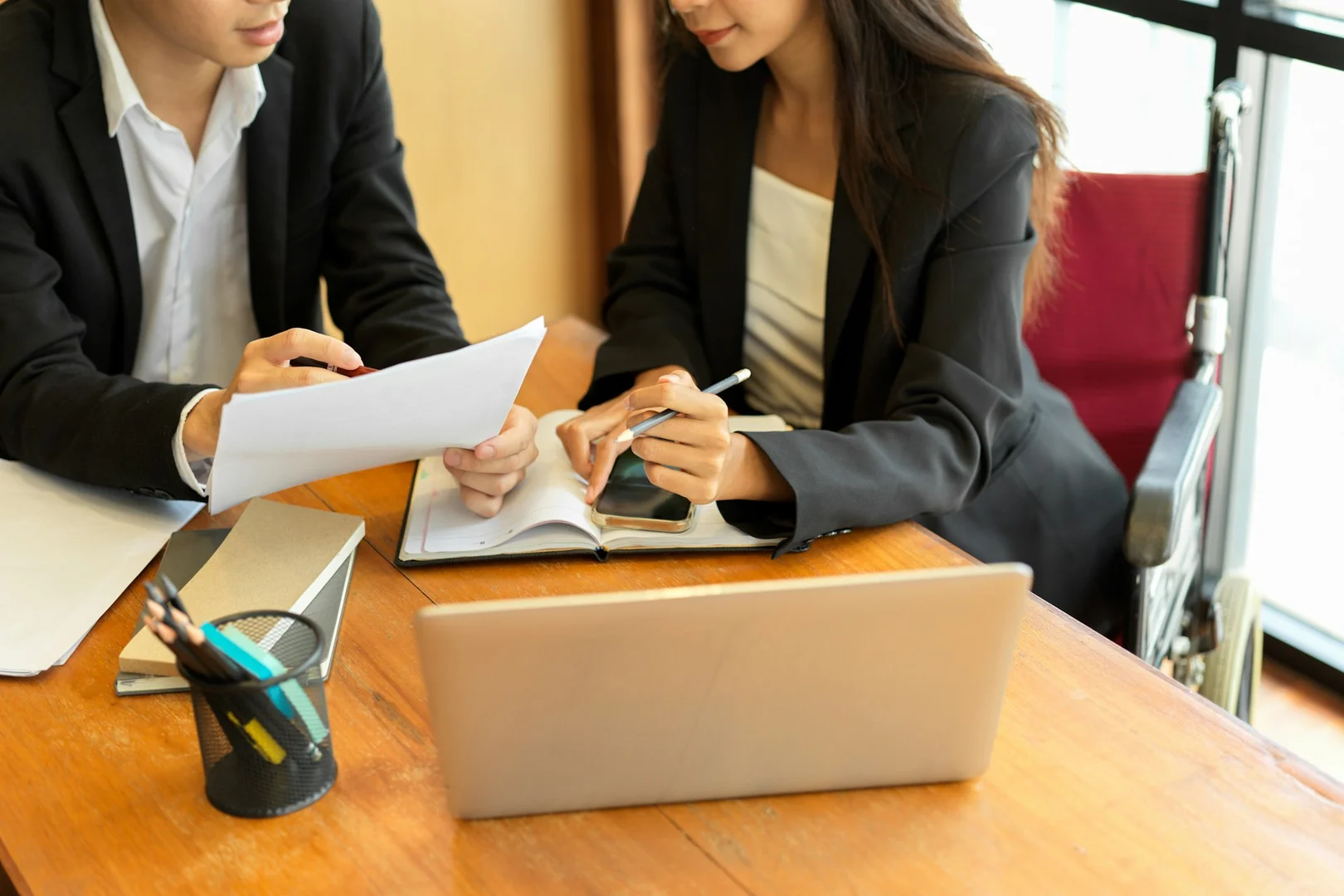 Parents or educators discussing documents at a desk, illustrating teamwork and decision-making in school councils.