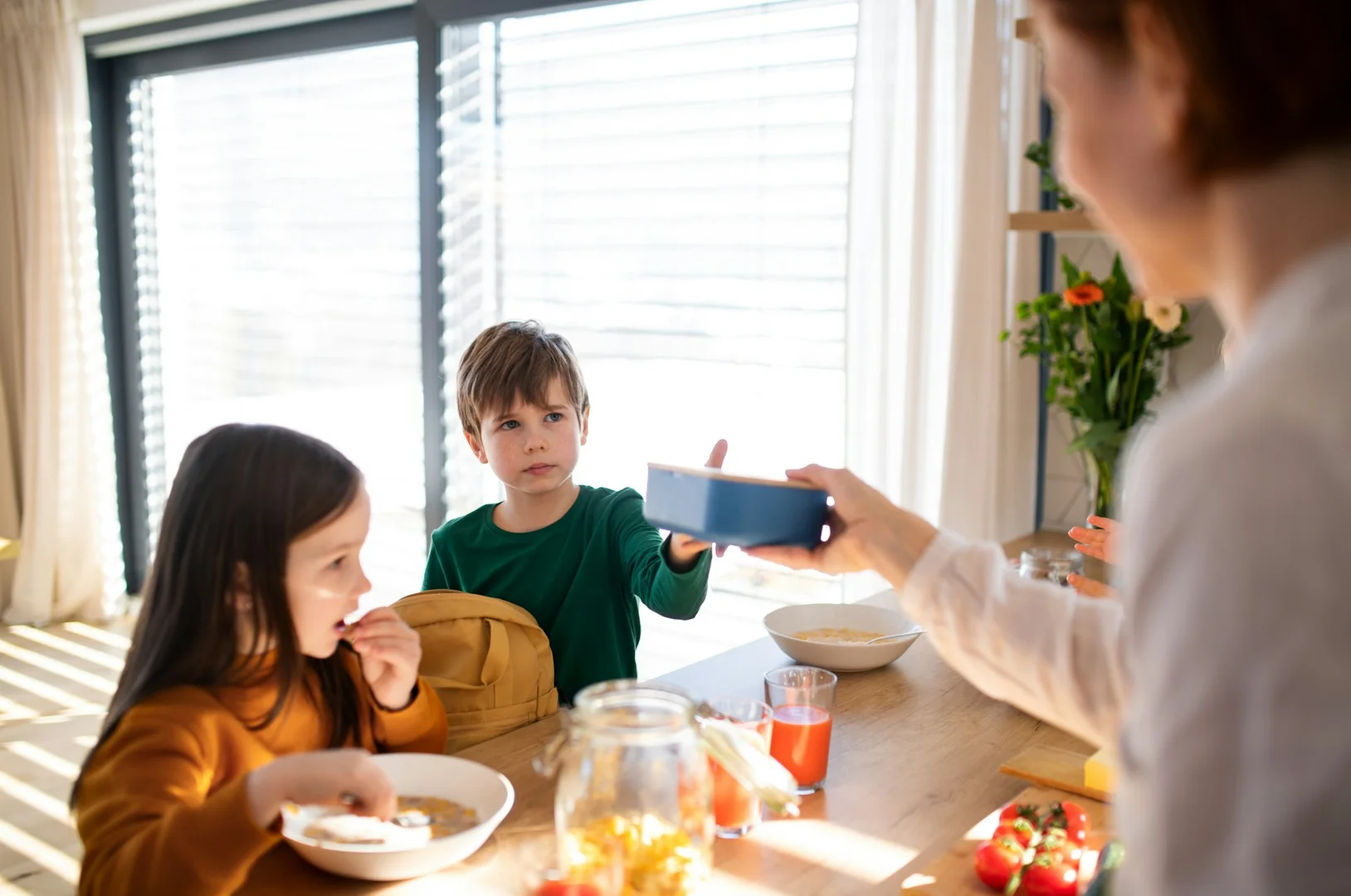 Parent handing lunch to children at home before school.