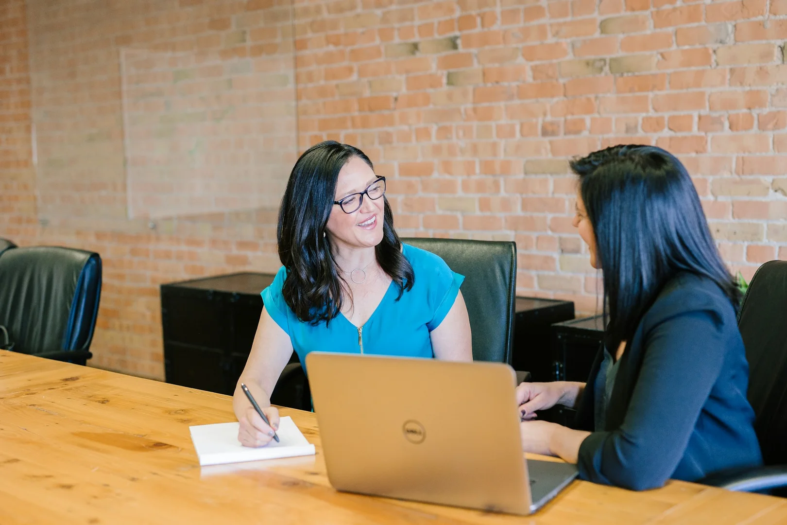 Two women having a positive discussion in a meeting room, symbolizing collaboration between.