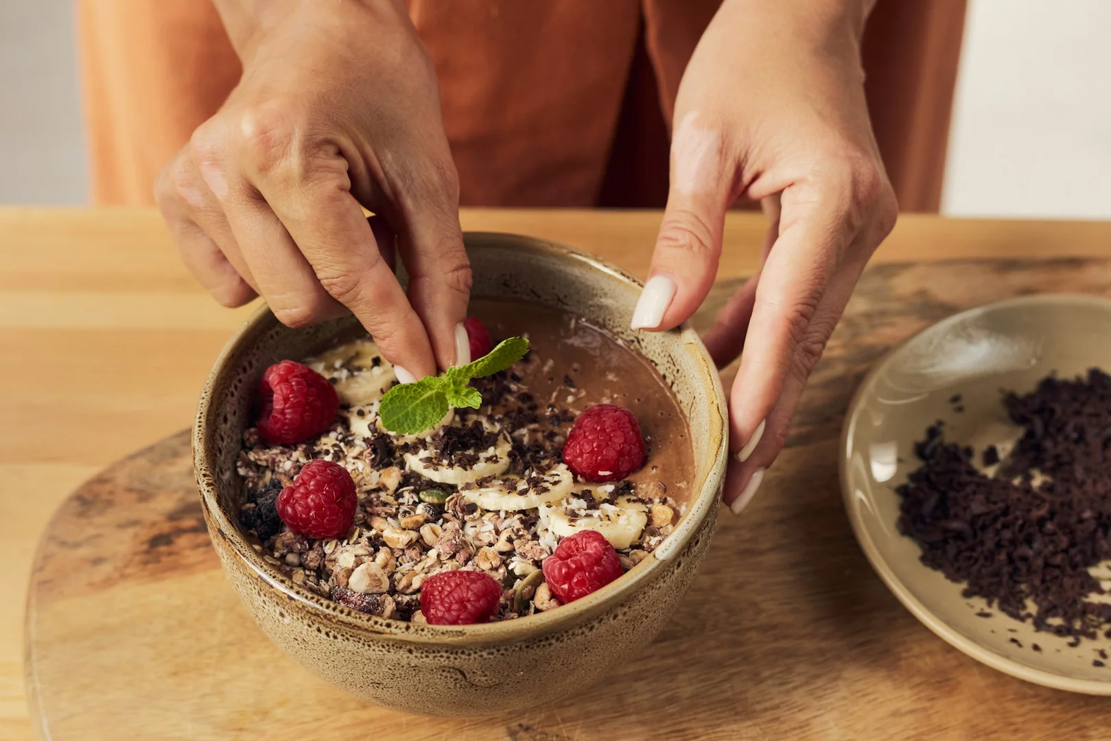 Hands decorating a healthy bowl with fruit and granola, representing nutritious options for hot lunch fundraising events.