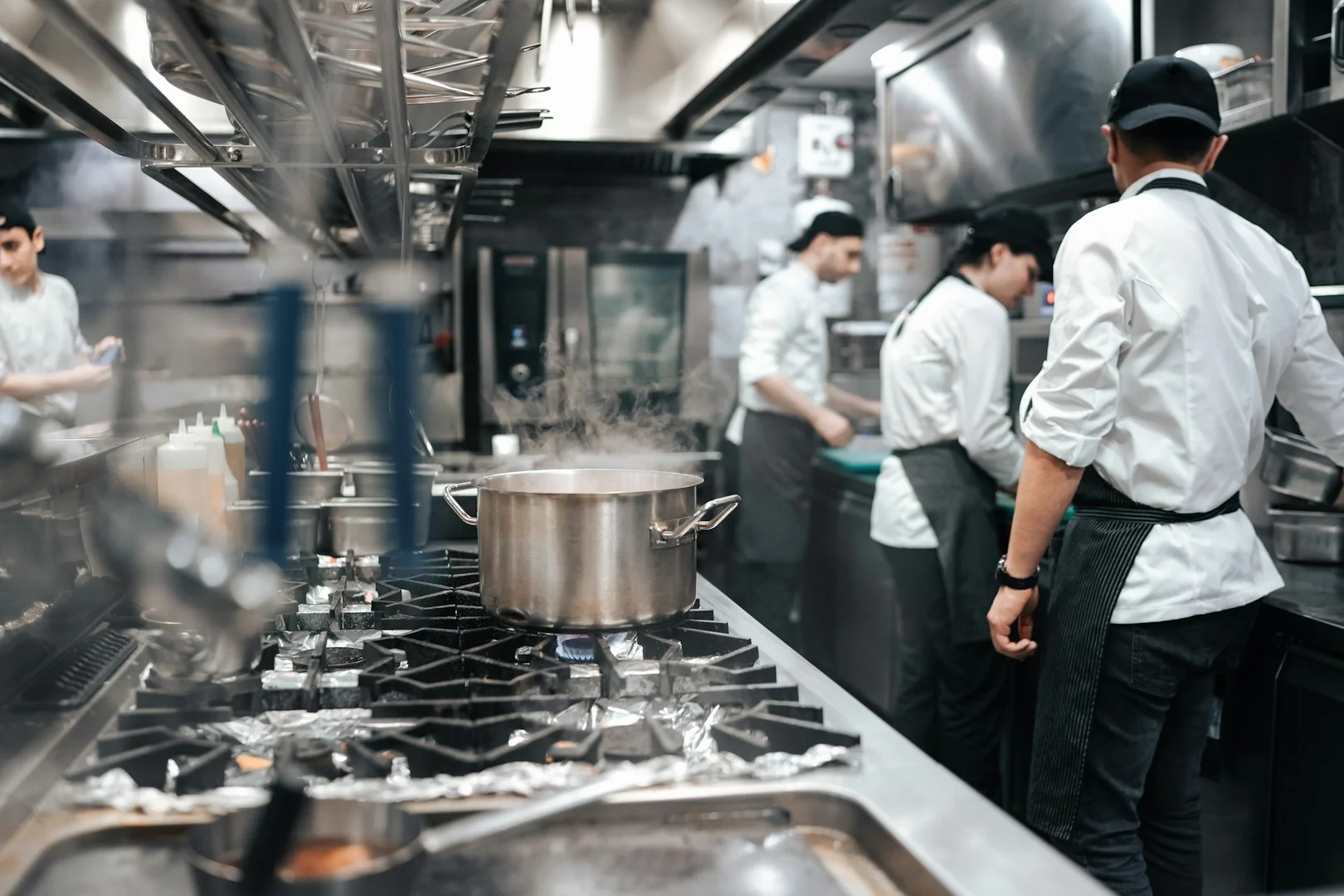 Restaurant kitchen staff preparing batch meals for school lunch catering.