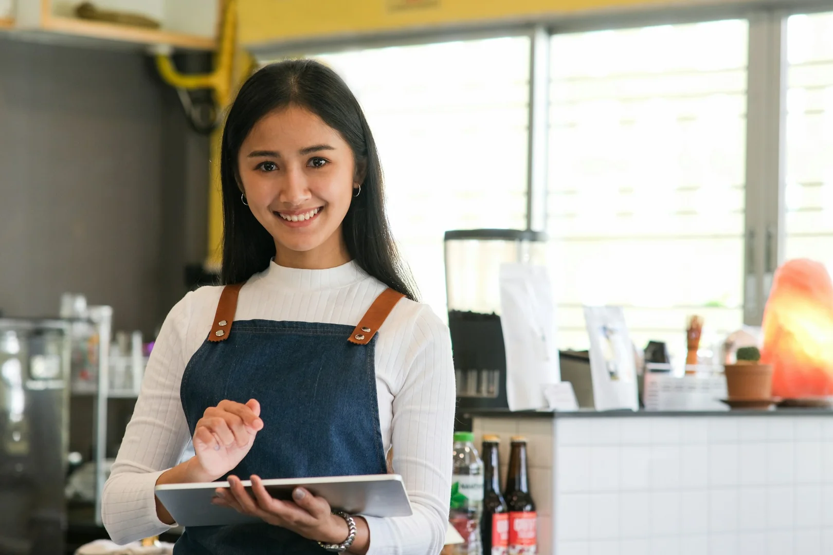 Smiling restaurant owner using a tablet, representing how vendors partner with schools through LunchUp.