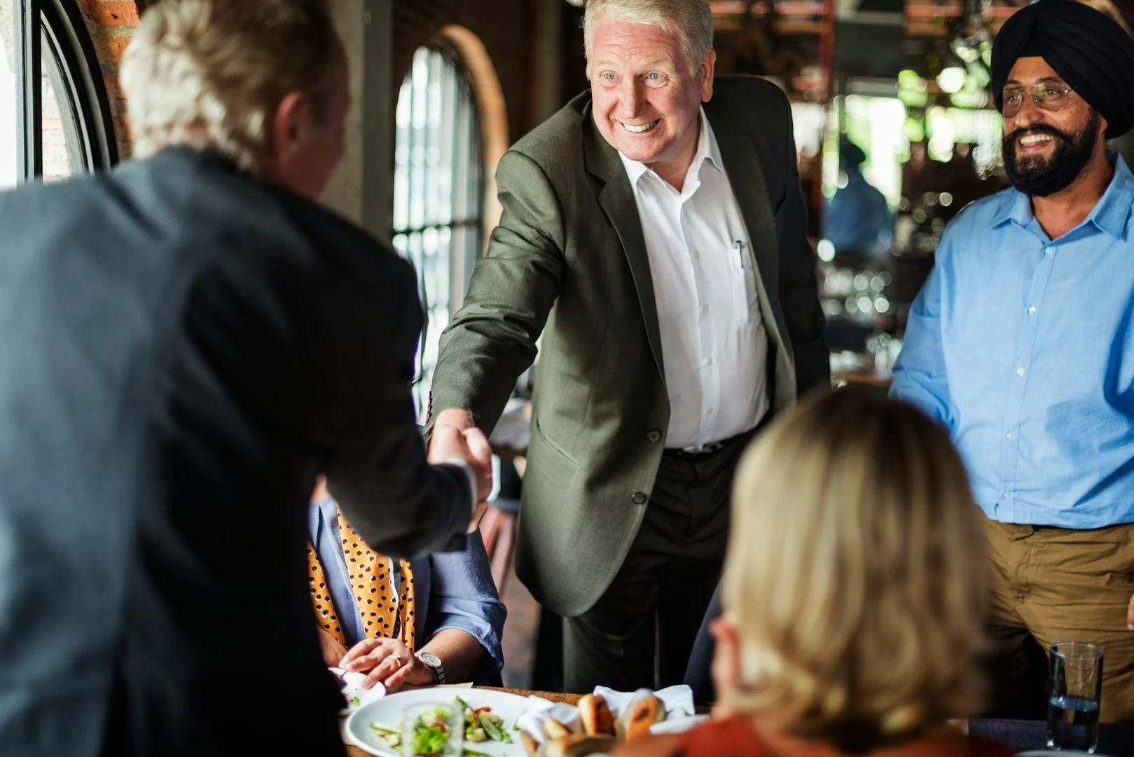 Restaurant owner shaking hands with a school representative to form a lunch program partnership.