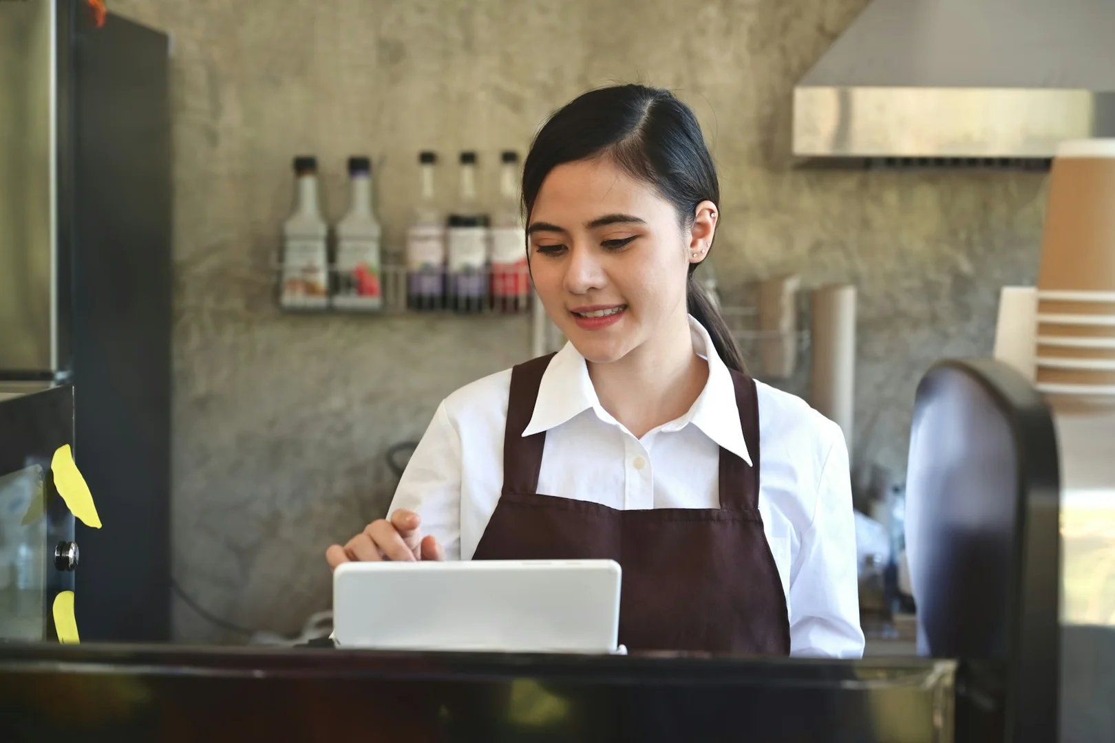 Restaurant staff using a tablet to manage digital school lunch orders and vendor partnerships.