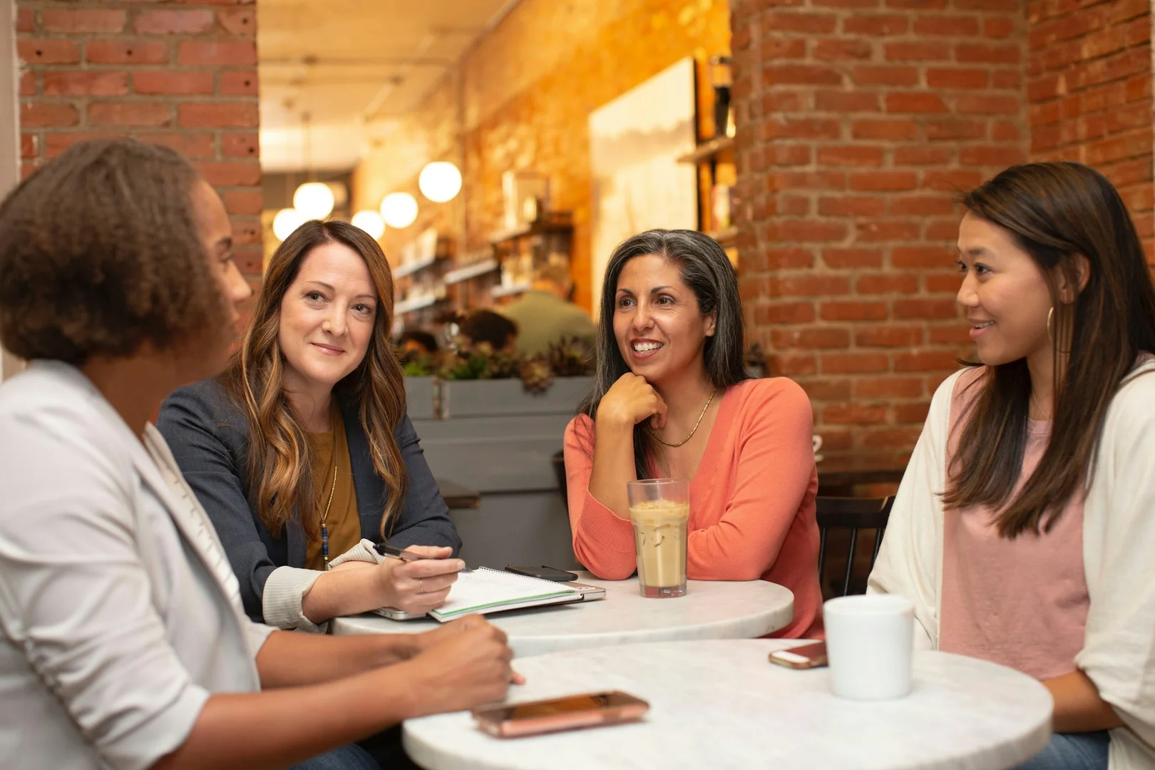 Group of people meeting in a café discussing community impact and school lunch program success.