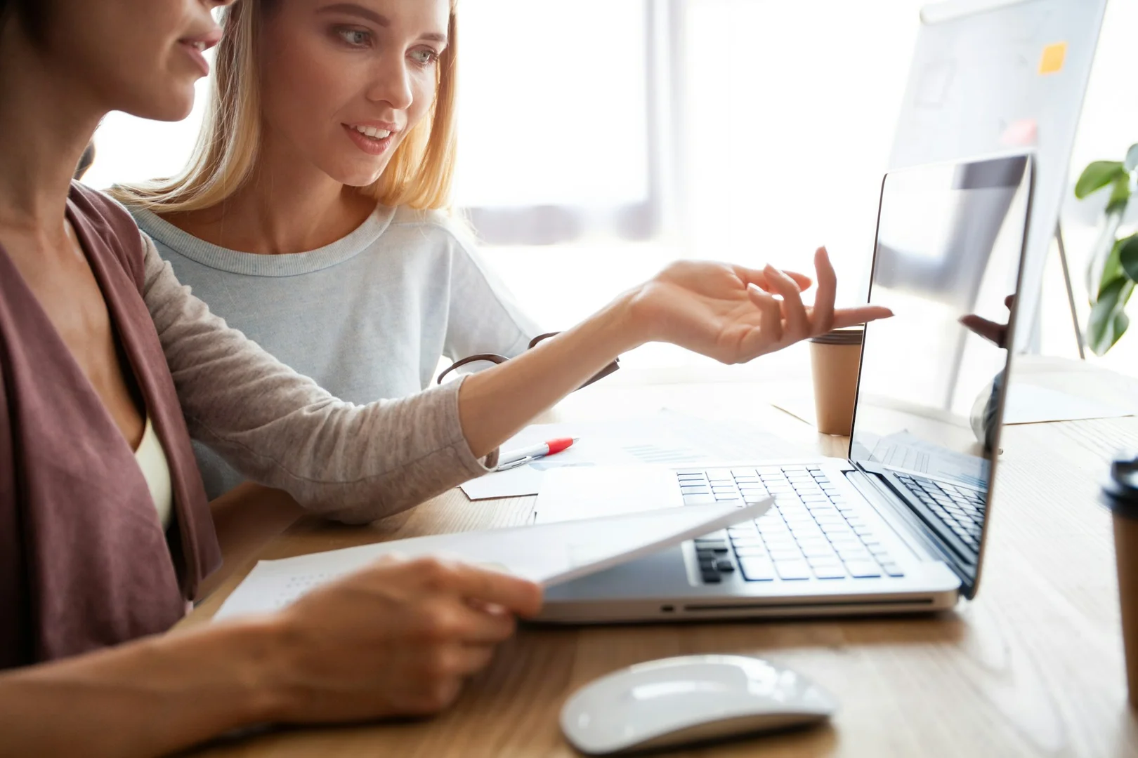 Two women reviewing school plans on a laptop, representing digital collaboration in school council activities.