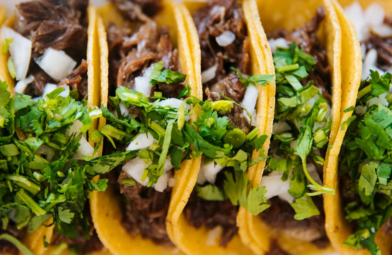 Close-up of fresh tacos with beef, onions, and cilantro for a themed school lunch fundraiser.
